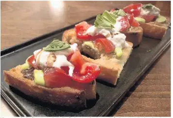  ??  ?? Vibrant, juicy chunks of tomato were bathed in a fresh pesto aioli and mozzarella for the restaurant’s take on bruschetta.