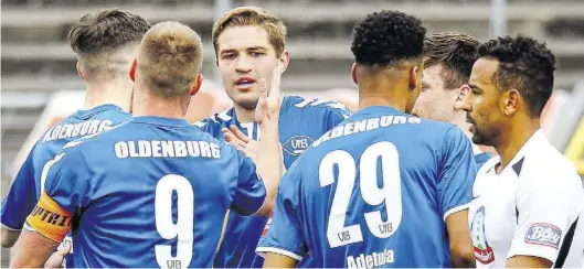  ?? BILD: Volkhard Patten ?? Jubel in Blau, Frust in Weiß: Die Oldenburge­r feiern den ersten Treffer von Marten Schmidt (Dritter von links), während Jeddelohs Ex-VfB-Er Shaun Minns (rechts) frustriert zuschaut.