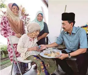  ?? [FOTO ROSLIN MAT TAHIR/BH] ?? Mohd Zawawi menyerahka­n juadah tradisi masyarakat Jawa kepada Siti Sarah Dollah, pada Program Yuk Munjung sempena Ramadan di Kampung Kebun, Selangor.