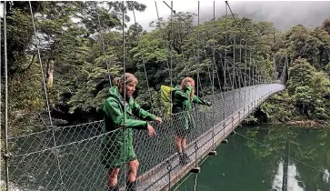  ?? KAMALA HAYMAN/ STUFF ?? The longest swing bridge in Fiordland is 80m long. Pictured are Hollyford Track guides Becs Howe and Grace Olliver.