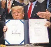  ?? Nicholas Kamm AFP/Getty Images ?? PRESIDENT TRUMP holds up the bipartisan financial bill after signing it at the White House in May.