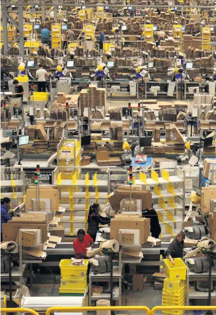  ??  ?? Online emporium:
Amazon employees at work in company’s huge warehouse in Peterborou­gh