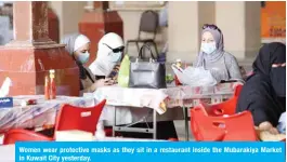  ??  ?? Women wear protective masks as they sit in a restaurant inside the Mubarakiya Market in Kuwait City yesterday.