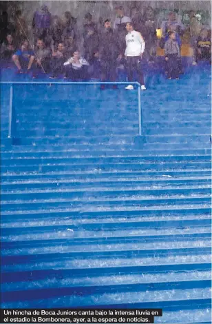  ??  ?? Un hincha de Boca Juniors canta bajo la intensa lluvia en el estadio la Bombonera, ayer, a la espera de noticias.