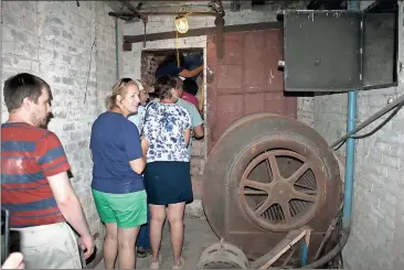  ?? John Popham / Rome News-Tribune ?? Sightseers walk past an old furnace and through the ancient fire door below the DeSoto Theatre during the Undergroun­d Rome Tour.