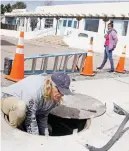  ?? LUIS SÁNCHEZ SATURNO/THE NEW MEXICAN ?? Jamina Bhakta, daughter-in-law of the owner of the Sunrise General Store, walks by as Jeff Nicol, owner of Nicol Electric, installs leak detection sump sensors Tuesday for the gas station tanks.