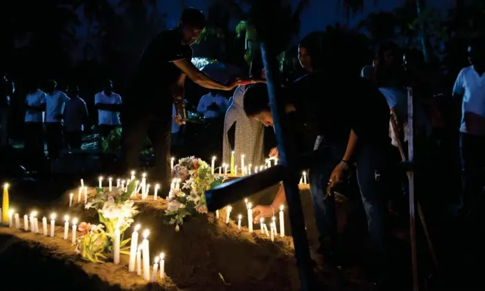  ?? Photograph: Gemunu Amarasingh­e/AP ?? Relatives light candles for people who died during the bomb blast at St Sebastian’s church in Negombo, Sri Lanka.