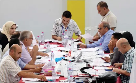  ?? AFP ?? Staff members of Tunisia’s Independen­t Higher Authority for Elections sort through ballots on Monday as they prepare the results of the presidenti­al vote at a sorting center in Ariana, north of Tunis.