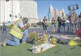  ?? FERAZZI / LOS ANGELES TIMES / TNS GINA ?? Contractor Robert Walker says a prayer after placing flowers and an American flag last week at the scene of a memorial for the victims of the mass shooting in Las Vegas.