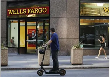  ?? (Bloomberg News/Peter Foley) ?? People pass a Wells Fargo & Co. branch last week in New York. The bank on Tuesday reported a quarterly loss for the first time since the financial crisis of 2008.