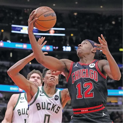  ?? CHARLES REX ARBOGAST/AP ?? Ayo Dosunmu beats the Bucks’ MarJon Beauchamp to the basket Thursday night, hours after getting word he’ll be playing during All-Star weekend.