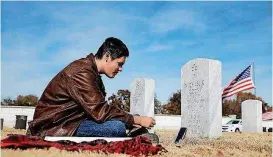  ?? [PHOTO BY MIKE SIMONS, TULSA WORD] ?? Dalton Coon sits Nov. 10 at the grave of his father, Staff Sgt. Michael K. Coon, who committed suicide after multiple deployment­s. Phillip Coon, Dalton’s grandfathe­r, is trying to raise awareness about veterans’ suicides.