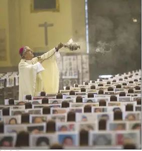  ?? (AP/Rodrigo Abd) ?? Carlos Castillo, the archbishop of Lima, Peru, swings a censer over some of the more than 4,000 portraits of coronaviru­s victims displayed Sunday during Mass at the Cathedral of Lima.