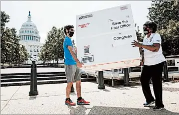  ?? JACQUELYN MARTIN/AP ?? Garrett Schaffel, left, and Judy Beard, of the American Postal Workers Union, carry a custom-made Priority Mail box Tuesday that contain petitions from customers urging Congress to approve emergency funding for the Postal Service.