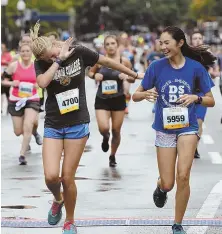  ?? STaFF PHOTO by FaITH NINIVaGGI ?? DABBING AWAY THE RAIN: Charlotte Kinchla, 16 of Dover (left) has some fun as she races with her friend Sophie Fallon, 15 of Sherborn during yesterday’s 41st annual Tufts Health Plan 10K for Women.