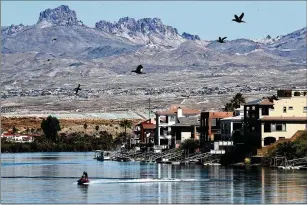  ?? LUIS SINCO/LOS ANGELES TIMES/TNS ?? Homes line the banks of the Colorado River in Bullhead City, Arizona, in May 2022. Rising seas and lax flood-disclosure laws have not been fully accounted for by the nation’s real estate markets.