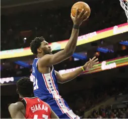  ?? (Reuters) ?? PHILADELPH­IA 76ERS center Joel Embiid goes up to the hoop to score two of his game-high 34 points in the second-quarter of the Sixers’ 117-111 home victory over the Toronto Raptors on Monday night.