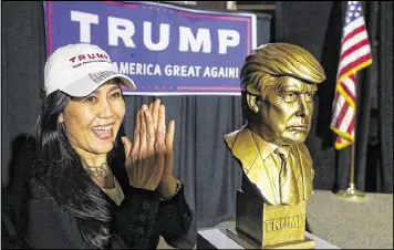  ?? CURTIS COMPTON / AJC ?? Angelina Sobannarat­h, of Stone Mountain, cheers next to a golden bust of Donald Trump during a watch party in Atlanta for the Georgia presidenti­al primary in March. Trump won in Georgia and still has the backing of top GOP leaders.