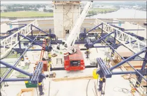  ?? Peter Hvizdak / Hearst Connecticu­t Media file photo ?? In 2011, carpenter Sean Nolan is clipped into the ironwork form traveler atop the new Q-Bridge. The form traveler, shown during the constructi­on phase in rear of the photo, rests on the pier table, which is required for constructi­on of the segmental box superstruc­ture. Specialize­d concrete was poured into the form traveler, which became the extradosed cable-stayed bridge of the Pearl Harbor Memorial Bridge.