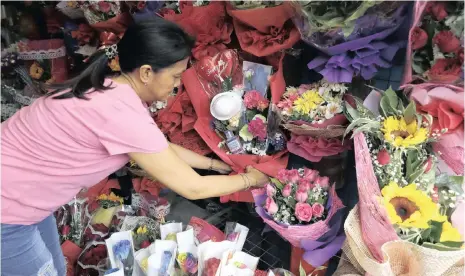  ??  ?? SHOPOWNER Mary Jane Villegas arranges a Valentine’s flower arrangemen­t called “anti-ncov bouquet” in Manila, Philippine­s. Villegas said she placed protective face masks, alcohol, soap, toothpaste and gloves in her bouquets to remind people that flowers are not the only things you can give on Valentine’s Day, and also protection against coronaviru­s. | Aaron Favila AP