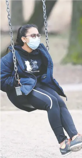  ?? DAN JANISSE ?? A woman wears a surgical mask while on a swing at the Mckee Park in Windsor on Thursday. Local authoritie­s are reminding citizens to take the pandemic seriously and to self-isolate after returning from travel.