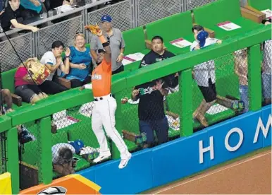  ?? MARK BROWN/GETTY IMAGES ?? Marlins center fielder Marcell Ozuna steals a home run from Dodgers right fielder Enrique Hernandez in the sixth inning.