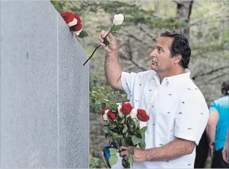  ?? ANDREW VAUGHAN THE CANADIAN PRESS ?? Stephen Thompson, from Atlanta, Ga., places roses as he remembers his father Ernest Thompson, who died in the crash of Swissair Flight 111 Sept. 2, 1998, at a memorial service at Bayswater Beach, N.S. on Sunday.