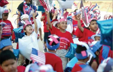  ?? TIM MONZINGO — THE DAILY SENTINEL VIA AP ?? Brooks-Quinn Jones Elementary School students wave flags over their heads as they prepare to march in the school’s annual Independen­ce Day Parade on Tuesday in Nacogdoche­s, Texas. Students decorated their bicycles and battery-powered cars, or walked along with parents and teachers during the parade.