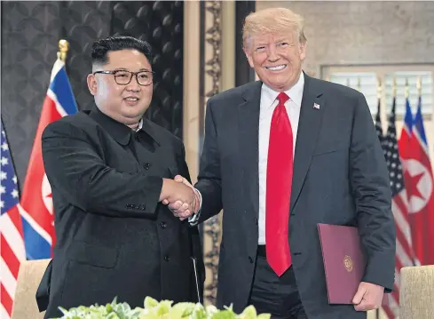  ?? AFP ?? US President Donald Trump and North Korea’s leader Kim Jong-un shake hands following a signing ceremony during their historic US-North Korea summit, at the Capella Hotel on Sentosa island in Singapore yesterday.