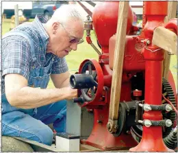  ??  ?? Robert Swanson of West Fork works on his 1 1/4 HP hit and miss engine on Friday at the Tired Iron of the Ozarks show in Gentry. The show featured a wide variety of old engines and machines.