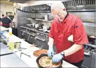  ?? Peter Hvizdak / Hearst Connecticu­t Media ?? Atillio Marini, chef and owner of the Cast Iron Chef Chop House and Oyster Bar in New Haven puts on the finishing touches of his cast-iron pizza creation on Tuesday that will part of his new restaurant in Milford.