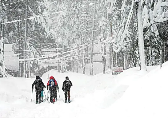  ?? PHOTOS BY BROOKE HESS-HOMEIER / AP ?? A group of friends ski on a residentia­l street during a snowstorm Saturday in Truckee.