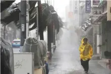  ?? Reuters ?? A man walks in heavy rain and wind caused by Typhoon Trami in Naha, on Japan’s island of Okinawa.