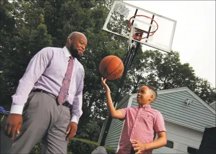  ?? Christian Abraham / Hearst Connecticu­t Media ?? Stacey Pierre-Louis and his son Eliah, 9, at their Trumbull home Friday. Eliah hid from a Trumbull police cruiser that passed by as he was playing basketball in his driveway in June, a scene captured in a now-viral video shown in the screengrab below.