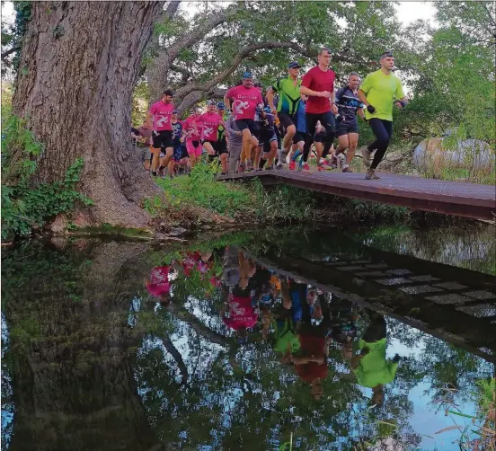  ?? CHRIS LEBLANC FOR AMERICAN-STATESMAN PHOTOS ?? Racers run across a footbridge at Colorado Bend State Park at the start of the Howl at the Moon Adventure Race on Oct. 21.