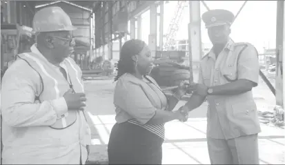  ??  ?? Permanent Secretary of the Ministry of Public Security Daneilla McCalmon (centre) handing over the keys to the boat to Director of Prisons (ag) Gladwin Samuels. (Department of Public Informatio­n photo)