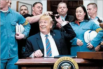  ?? MICHAEL REYNOLDS/EPA ?? President Donald Trump hands out pens to workers after signing executive orders on steel and aluminum tariffs.