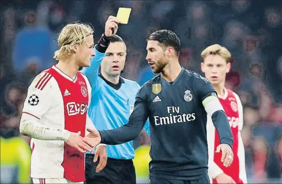  ?? WOLFGANG RATTAY / REUTERS ?? Sergio Ramos se disculpa con Dolberg por la falta mientras Damir Skomina enseña tarjeta amarilla al capitán blanco