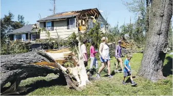  ?? MATT ROURKE, THE ASSOCIATED PRESS ?? People walk by a downed tree and storm-damaged house in Fort Washington, Pennsylvan­ia in the aftermath of downpours and high winds from the remnants of Hurricane Ida that hit the area.