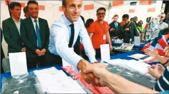  ??  ?? 法國總統馬克宏(前)15日在總統府艾麗榭­宮前的活動攤位與民眾­握手。 （路透）