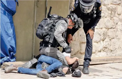 ?? Agence France-presse ?? ↑
Policemen detain a Palestinia­n in Jerusalem’s Old City on Monday.