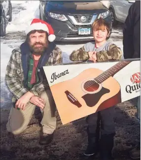  ?? Vinny Rodriguez / Contribute­d photo ?? Vinny Rodriguez has been giving away guitars during the COVID-19 pandemic as a way to keep children busy and interested in music. He is pictured here with a child named Logan.