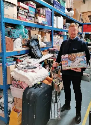  ??  ?? ●●Ryan Perkins from St Ann’s Hospice prepares for the bargains sale at the distributi­on centre in Reddish