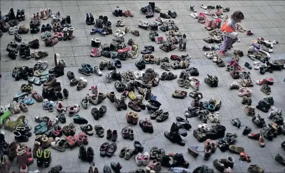  ?? CHRISTOPHE­R FURLONG / GETTY ?? Una niña busca entre los zapatos donados por ciudadanos húngaros en la estación de Keleti, en Budapest