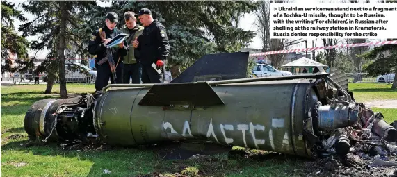  ?? Andriy Andriyenko ?? > Ukrainian servicemen stand next to a fragment of a Tochka-U missile, thought to be Russian, with the writing ‘For children’, in Russian after shelling at the railway station in Kramatorsk. Russia denies responsibi­lity for the strike