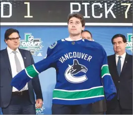  ?? The Associated Press ?? Quinn Hughes dons a Vancouver Canucks jersey after the Canucks selected him seventh overall during Friday’s draft in Dallas.