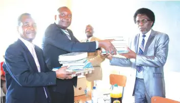  ??  ?? Mr Morris Mtisi and Mr Shame Isaki hands over educationa­l material to Chitakatir­a High School headmaster last Thursday