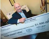  ?? DAVID ZALUBOWSKI/AP ?? Colorado State Treasurer Dave Young holds a replica of a $1,500 check to be sent to resident joint tax filers as a refund of surplus revenue Tuesday in Denver.