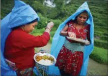  ?? NIRANJAN SHRESTHA — THE ASSOCIATED PRESS ?? In this file photo, a farmer, left, ritualisti­cally offers a small portion of food to god before eating her lunch while working at a rice field in Chunnikhel, Katmandu, Nepal.