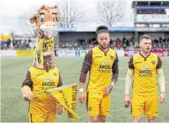  ?? REUTERS ?? Sutton United mascot Jenny the Giraffe with a face mask and players line up before the game against Hartlepool last week.